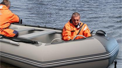 Inflatable boat with two people showing V-shaped keel and aluminum floorboards in marina dinghies