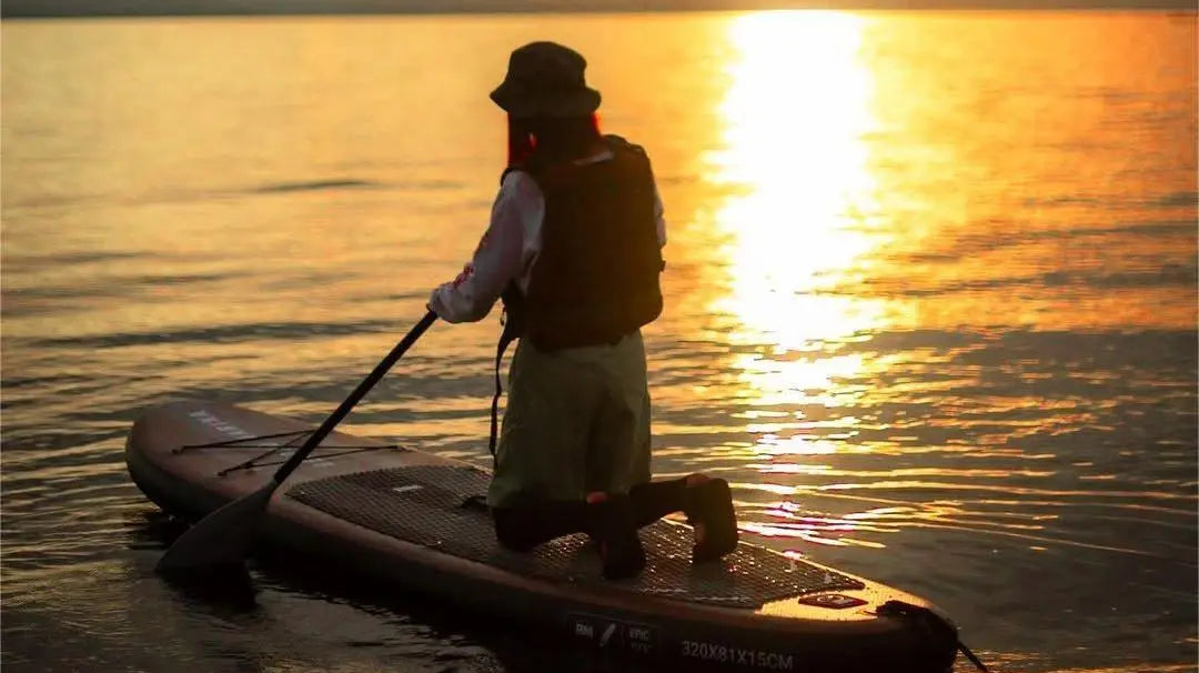 Paddleboarder kneeling on a wooden series paddle board in Paddling.com review