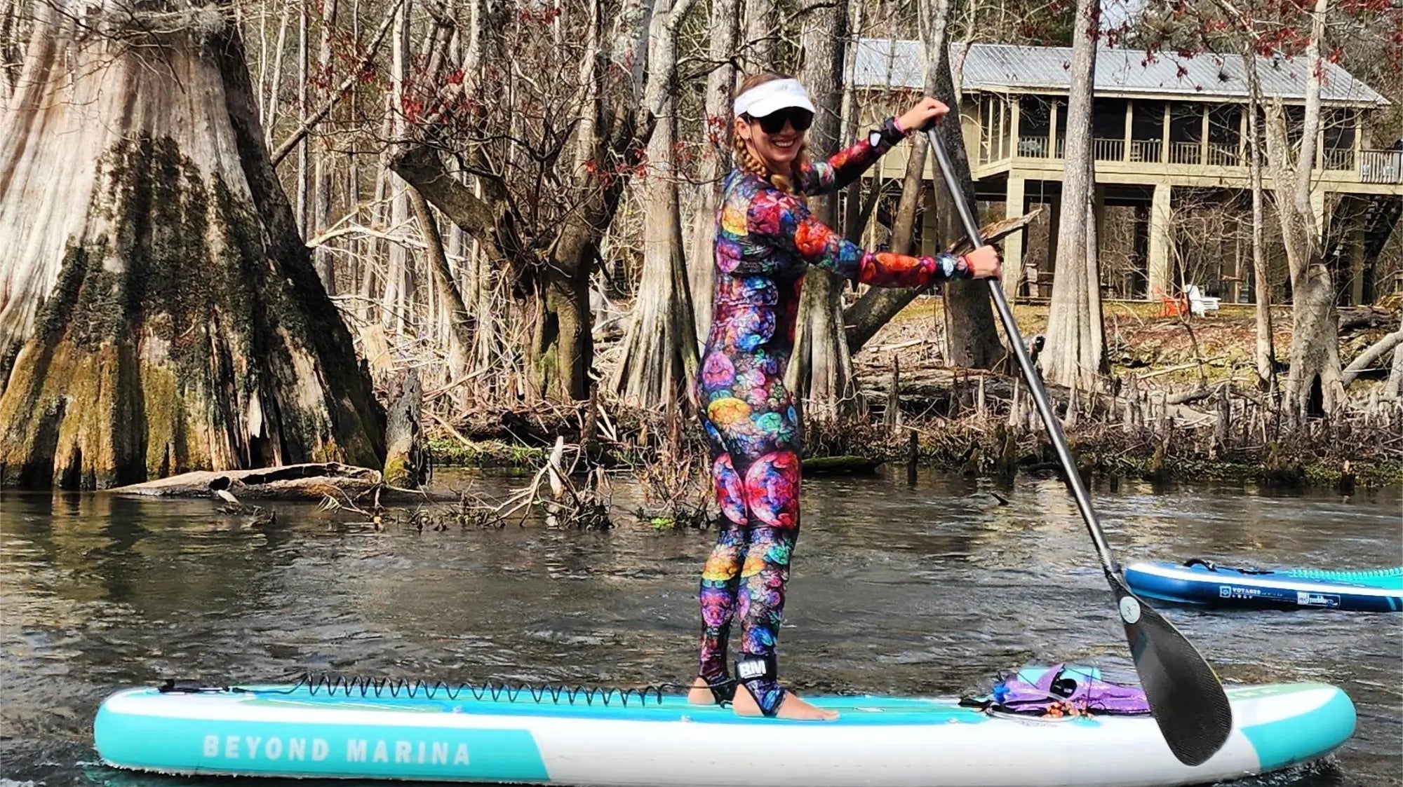 Stand-up paddleboarding with a colorful wetsuit and knees slightly bent for balance