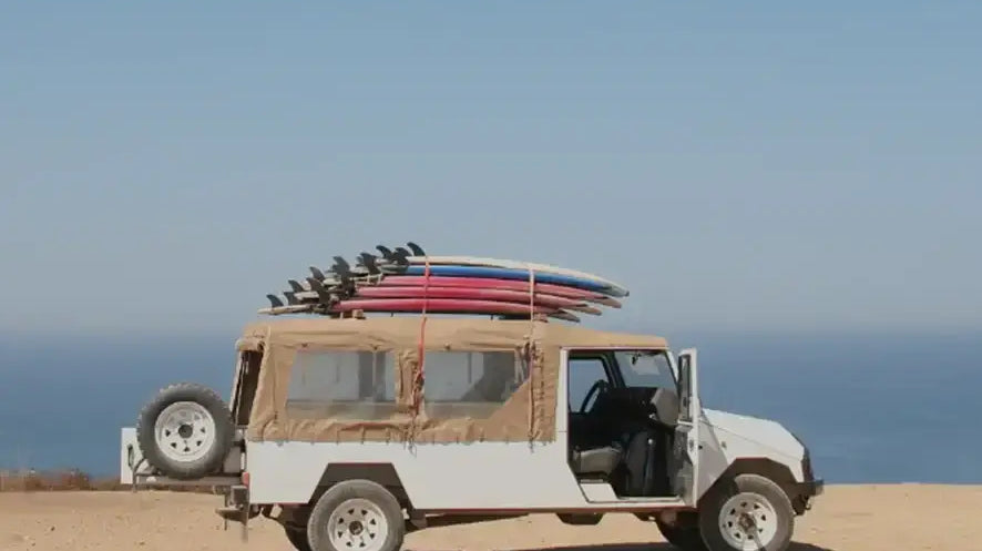 White Jeep with surfboards on top, ideal for transporting inflatable lure boats.