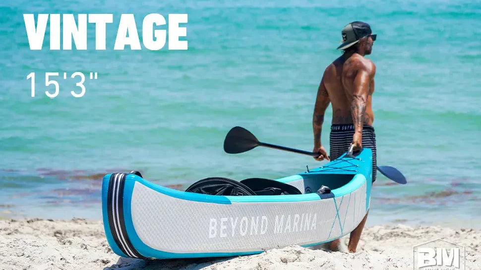 Man standing on beach with blue inflatable drop stitch kayak