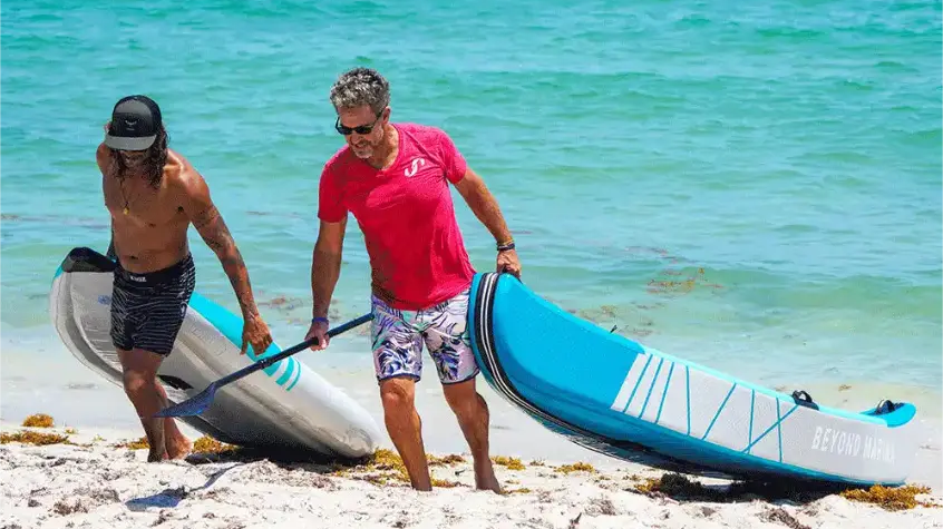 two people dragging inflatable two person kayaks