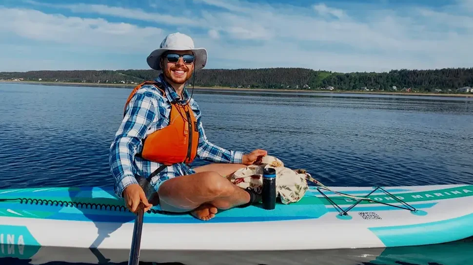 Woman in hat and sunglasses on high pressure paddle board.