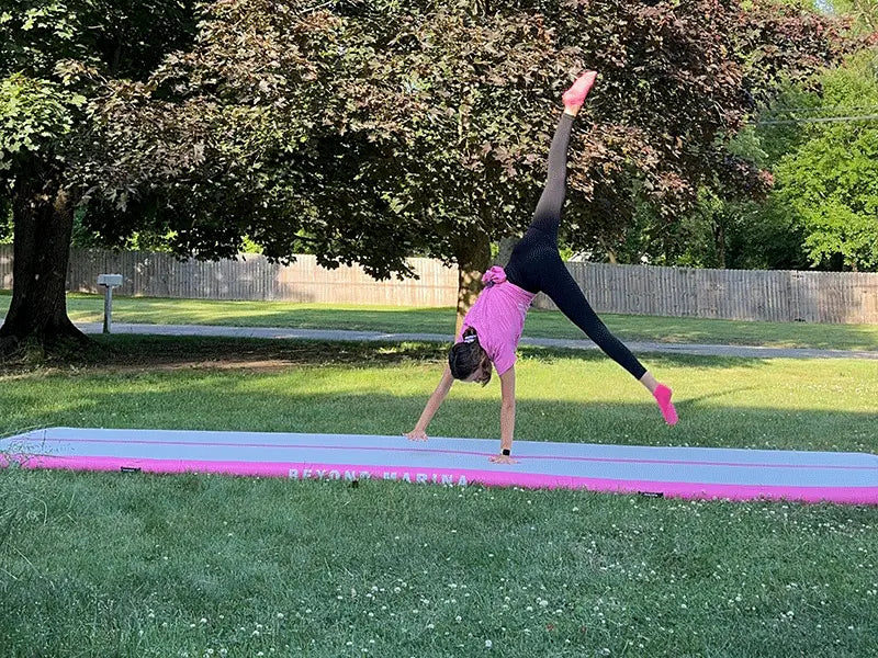Gymnast performing a cartwheel on pink and gray inflatable tumbling mats from Marina Air Track.