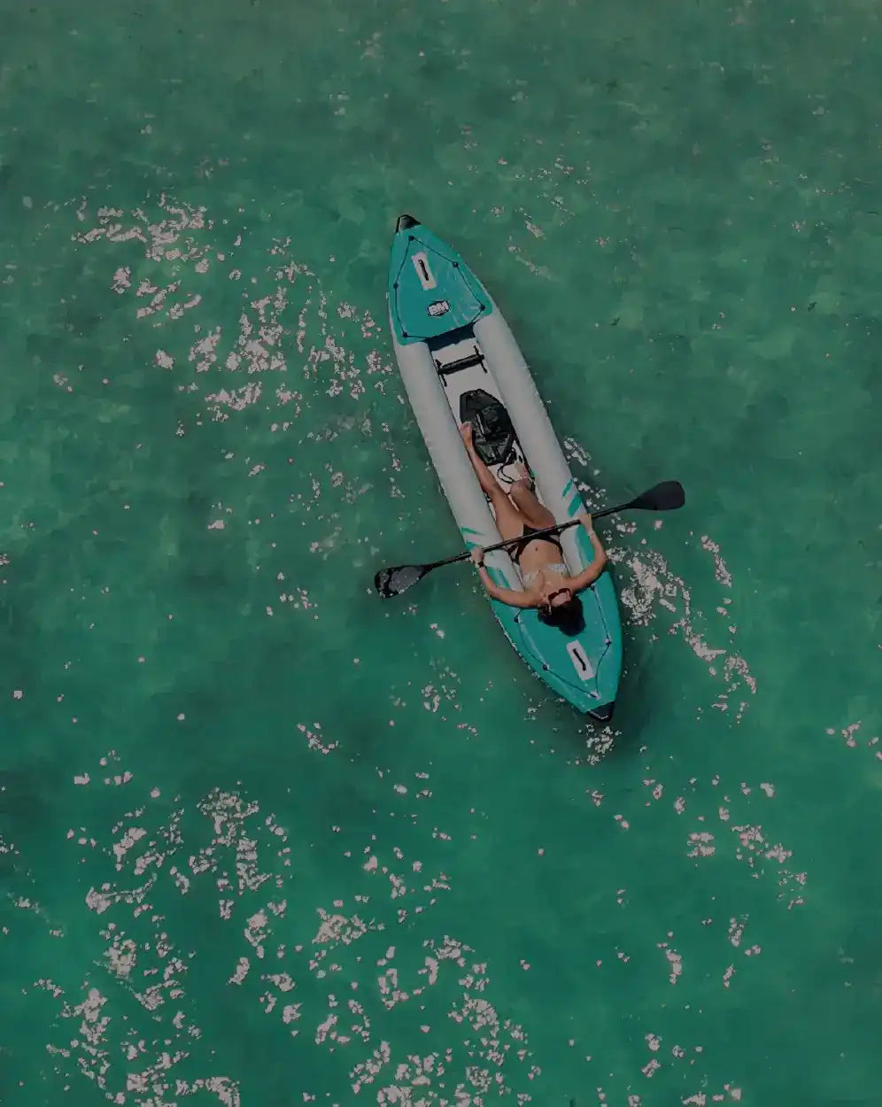 Turquoise and white inflatable kayak with a person.