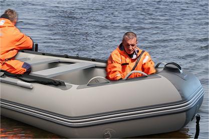 Inflatable boat with two people showing V-shaped keel and aluminum floorboards in marina dinghies