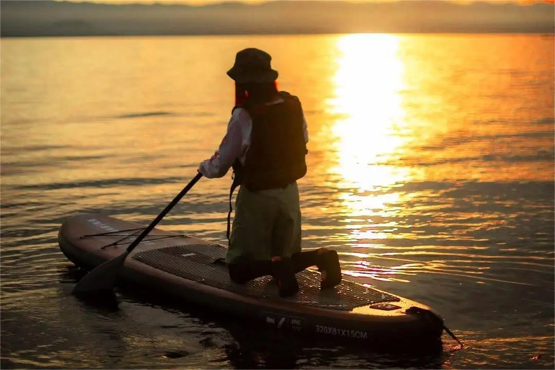 Paddleboarder kneeling on a wooden series paddle board in Paddling.com review