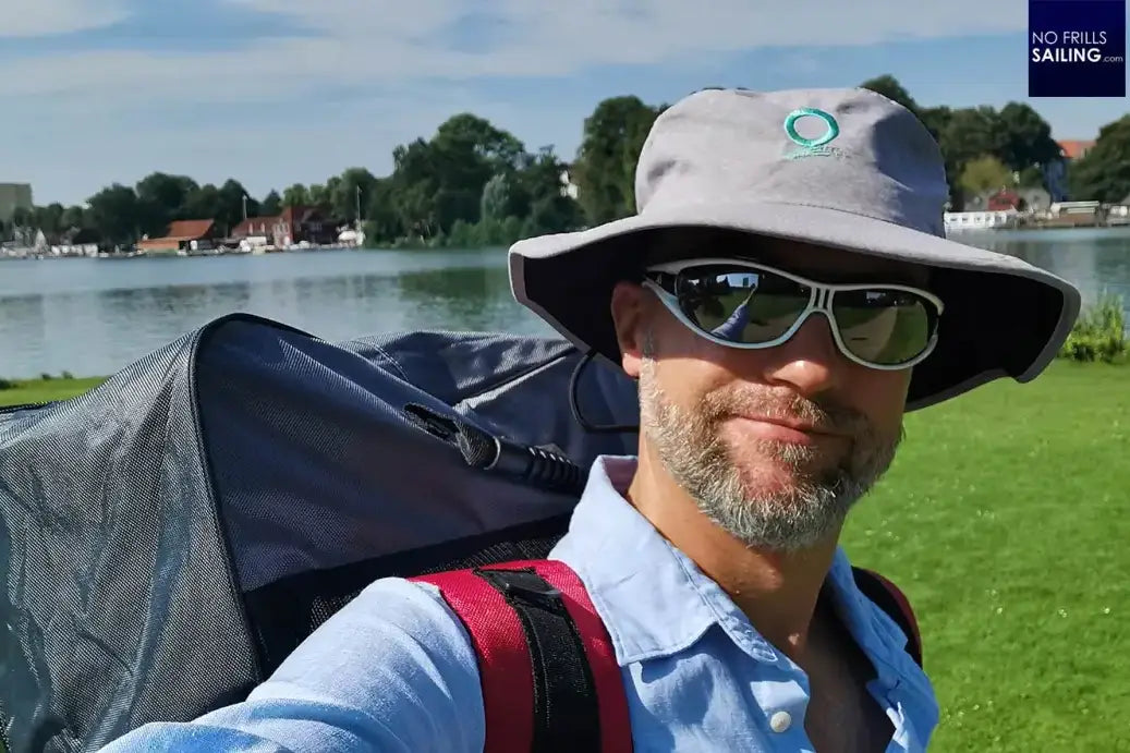 Man with backpack and sunglasses taking a selfie while stand-up paddleboarding adventure.