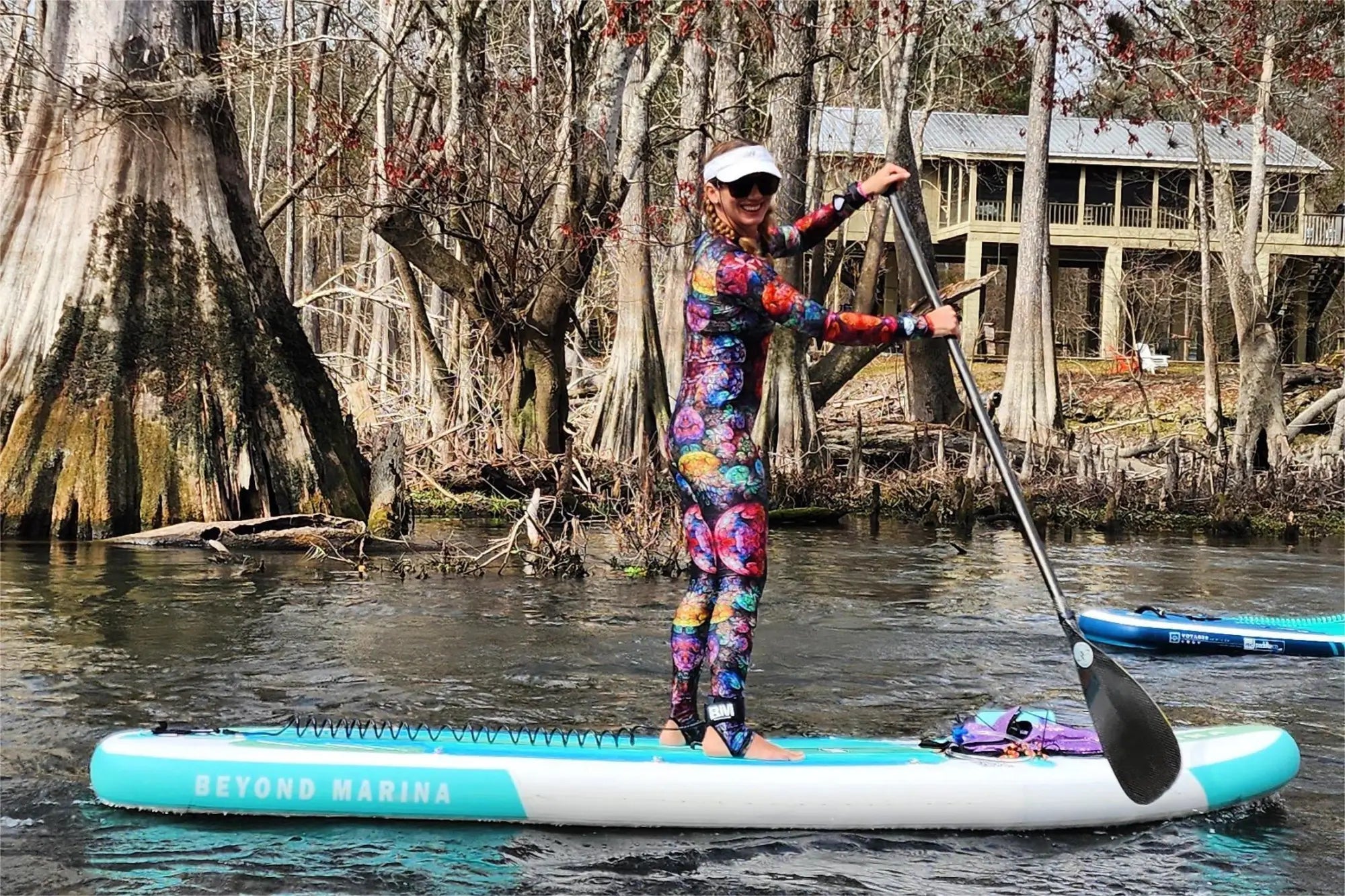 Stand-up paddleboarding with a colorful wetsuit and knees slightly bent for balance