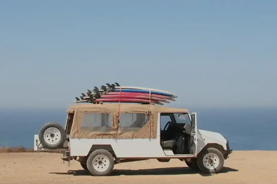 White Jeep with surfboards on top, ideal for transporting inflatable lure boats.