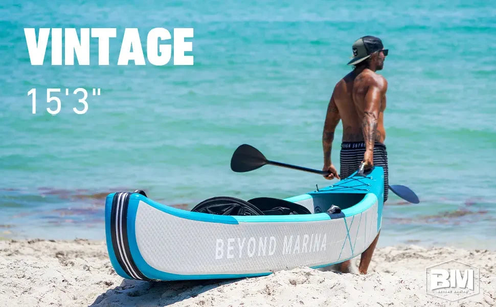 Man standing on beach with blue inflatable drop stitch kayak