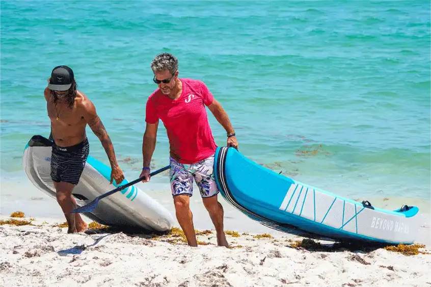 two people dragging inflatable two person kayaks