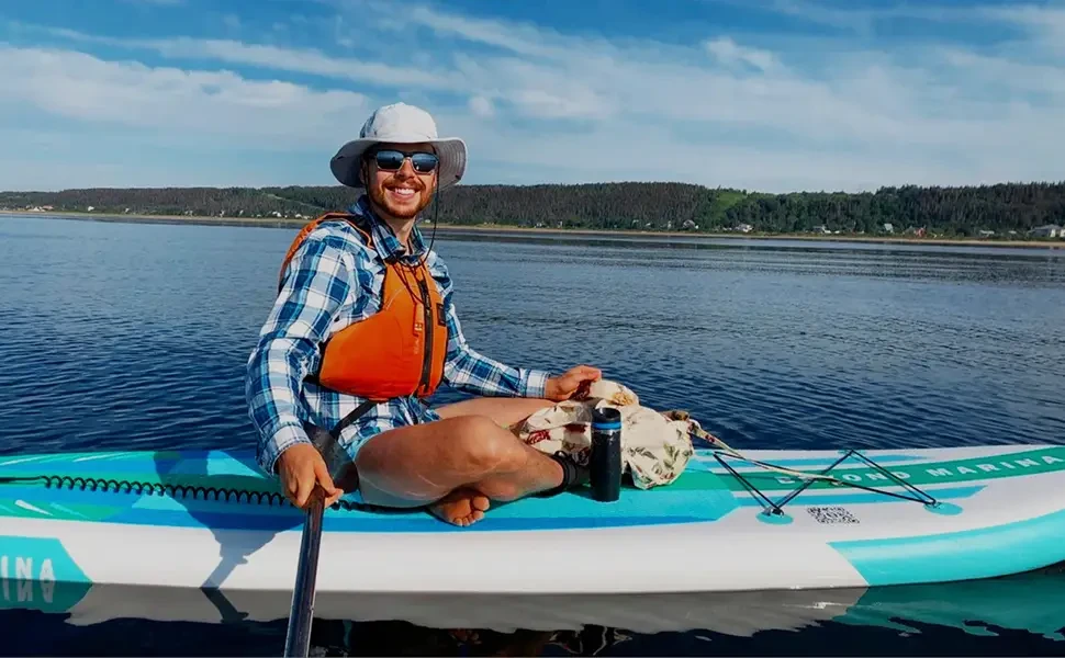 Woman in hat and sunglasses on high pressure paddle board.