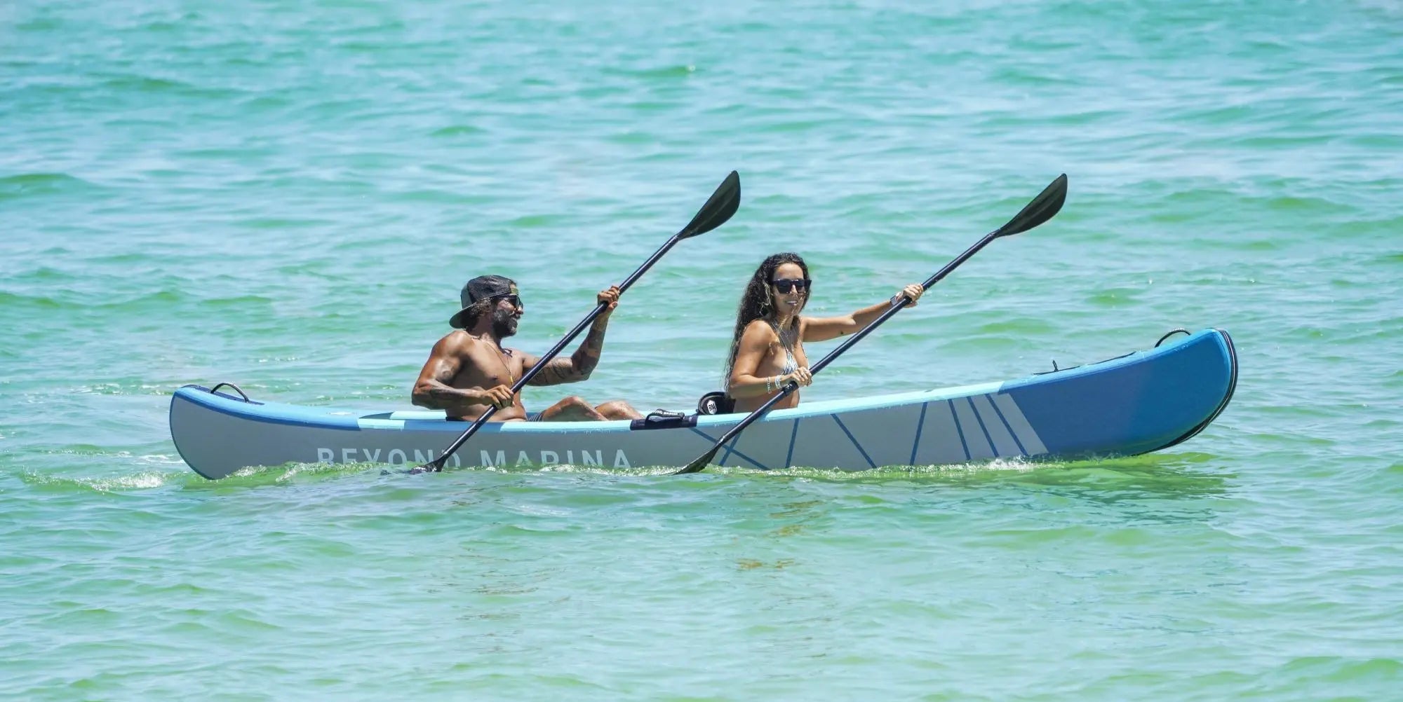 Two people paddling a kayak on clear blue water
