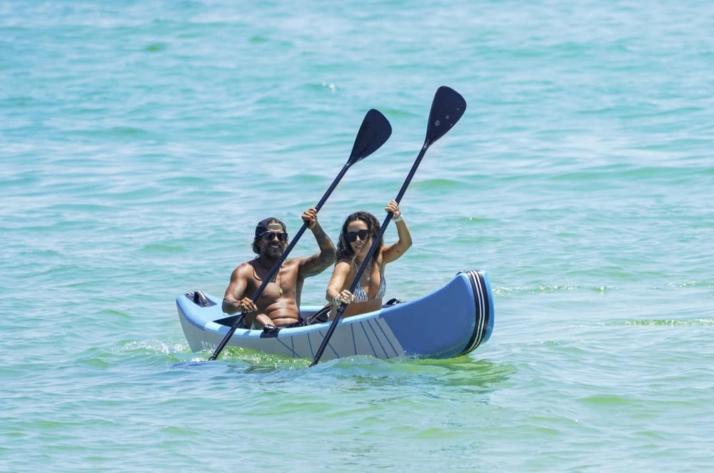 Two people paddling a kayak in clear blue water