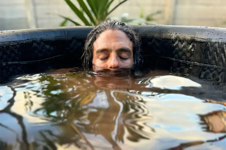 Man immersed in a dark tub.