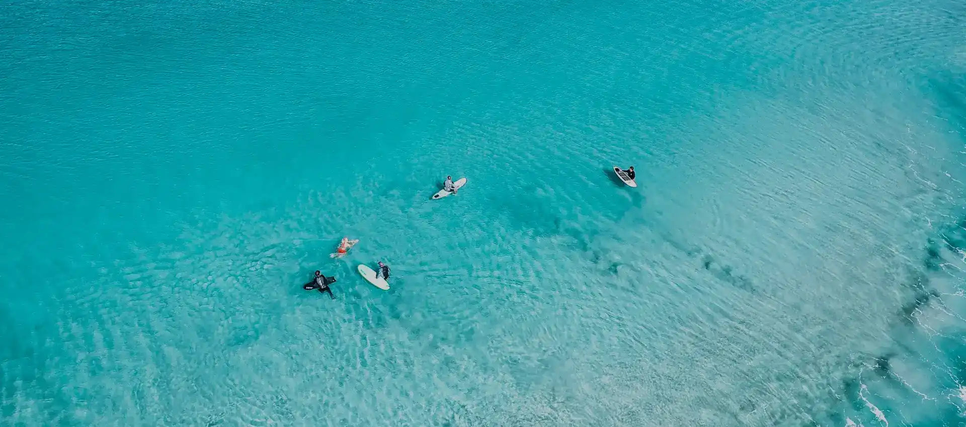 Turquoise ocean with surfers.